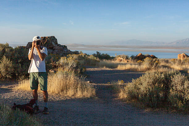 Young man photographs in arid climate above salt lake, Antelope Island State Park, Utah