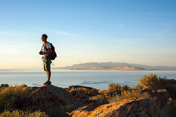 Young man photographer in arid climate above salt lake, Antelope Island State Park, Utah