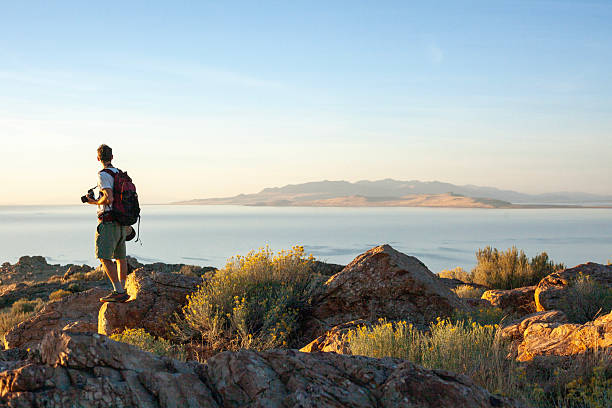 Young man photographer in arid climate above salt lake, Antelope Island State Park, Utah