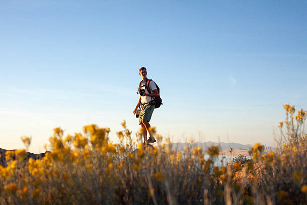 Young man photographer in arid climate above salt lake, Antelope Island State Park, Utah