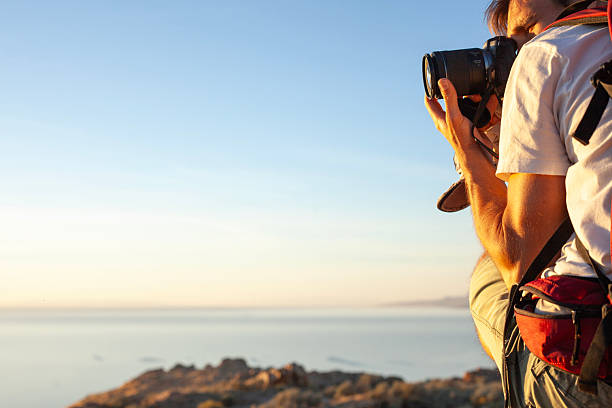 Profile view of man photographing in arid climate above salt lake, Antelope Island State Park, Utah