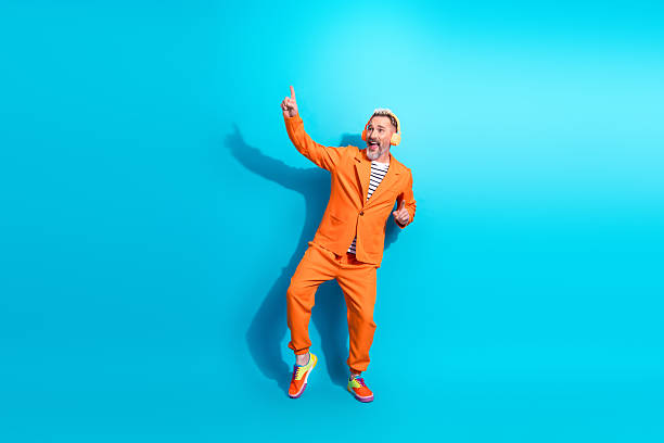 istock Charismatic middle aged man in vibrant orange suit making joyful gestures against a bright blue background 2212524176