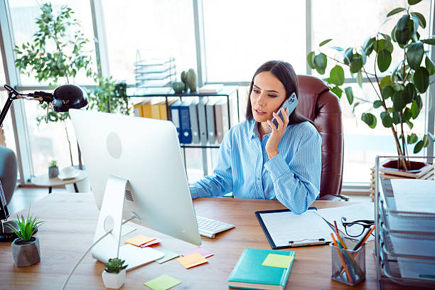istock Professional Woman Working in a Modern Office While on a Business Call Surrounded by Daylight and Organized Workspace 2212524446