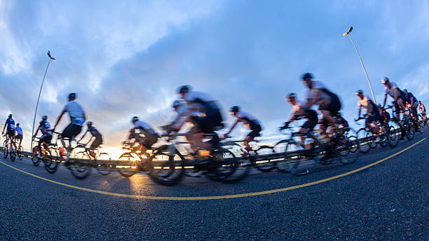 Cycling riders close-up morning dawn motion speed blur unrecognizable cyclists peleton on coastal road race highway.