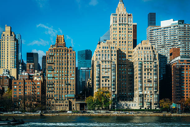 Scenic view of Manhattan's iconic skyline featuring historic architecture and a waterfront under a clear blue sky, showcasing New York City's urban charm and cultural significance.