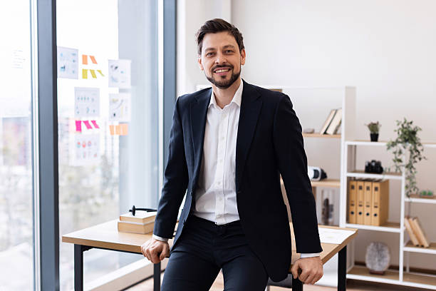 istock Confident businessman sitting on desk in modern bright office workspace 2212527676