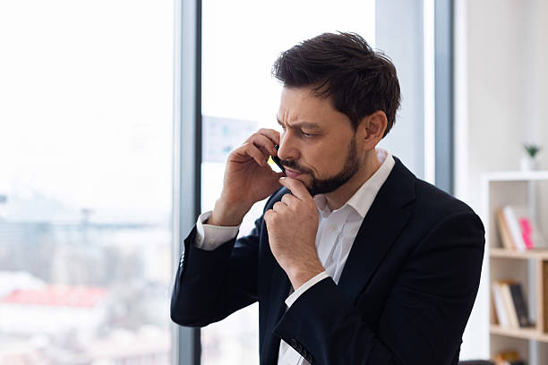 istock Businessman in office thinking while talking on phone near large window 2212527694