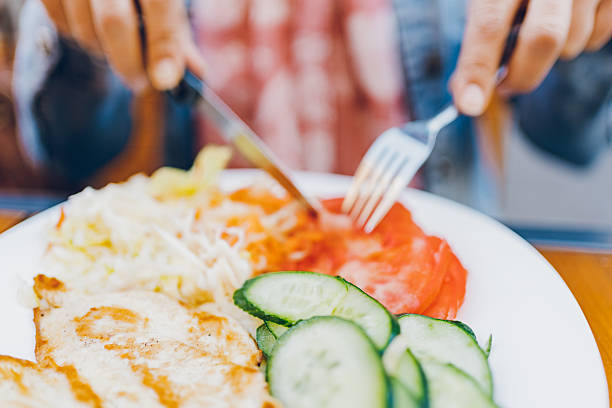 A woman eats chicken and salad in a restaurant.