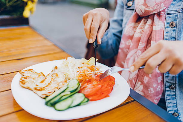 istock A woman eats chicken and salad in a restaurant 2212528294