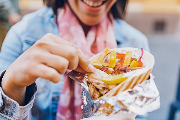 istock Young woman eating gyros 2212528561