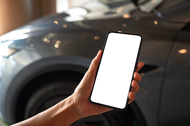 istock Using smartphone in front of car with blank screen 2212529864