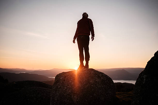 istock Hiker standing on rock enjoying inspiring sunset view from mountain peak 2212530271