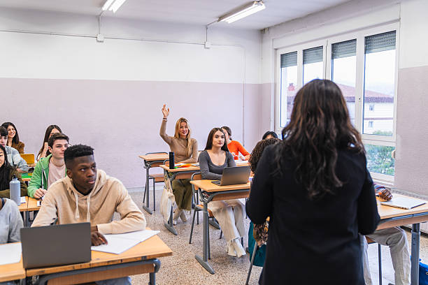 istock High school students raising hand in classroom during lesson 2212530682