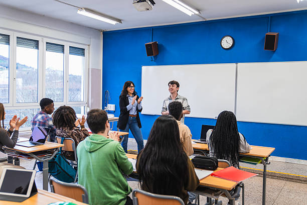 istock High school students applauding classmate and teacher in modern classroom 2212531365