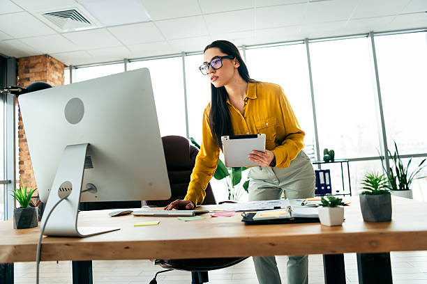 istock Young businesswoman working in a modern office workspace, reviewing documents and checking information on a computer monitor. 2212532051