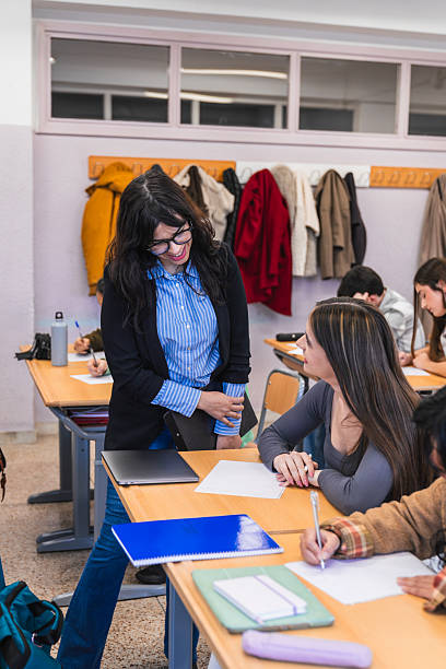 istock Smiling teacher helping female student during class in high school 2212532345