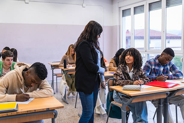 istock High school teacher helping students during exam in classroom 2212532895