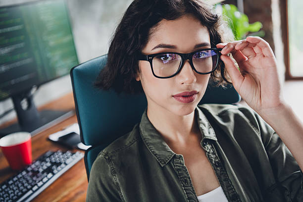 istock Young professional woman with glasses working in a modern office setting while focusing on a computer programming project 2212533757