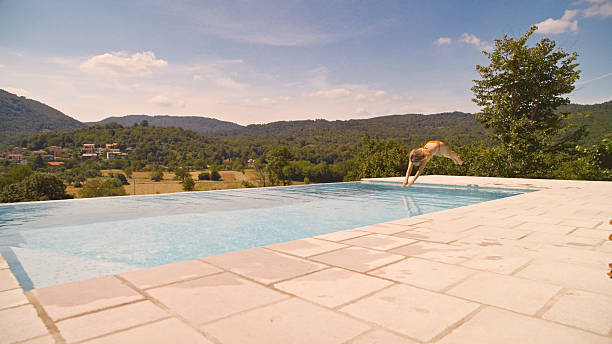 A daytime photo of a hotel's shared infinity pool with sun loungers during summer season, showcasing luxurious relaxation.
