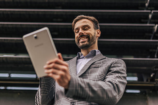 istock Smiling businessman using digital tablet in urban setting 2212535239