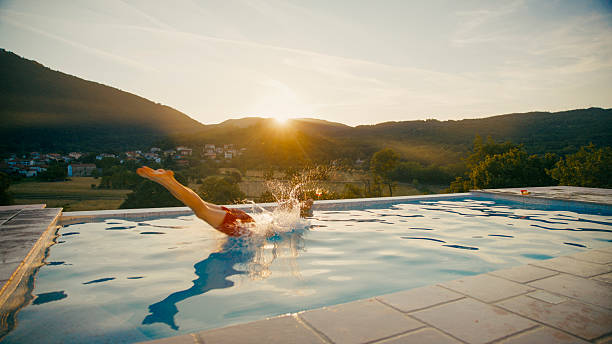 High angle view of man wearing red shorts swimming in a blue pool in sunny day at summer