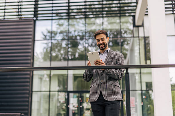 istock Smiling businessman using digital tablet outside office building 2212535506