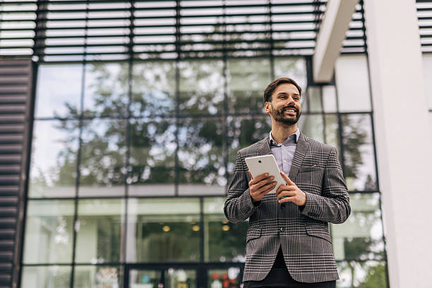 istock Smiling businessman holding digital tablet outside office building 2212535621