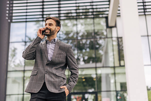 istock Businessman smiling while talking on phone outside office 2212535686