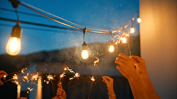istock Friends Celebrating with Sparklers Under String Lights at Dusk 2212535974