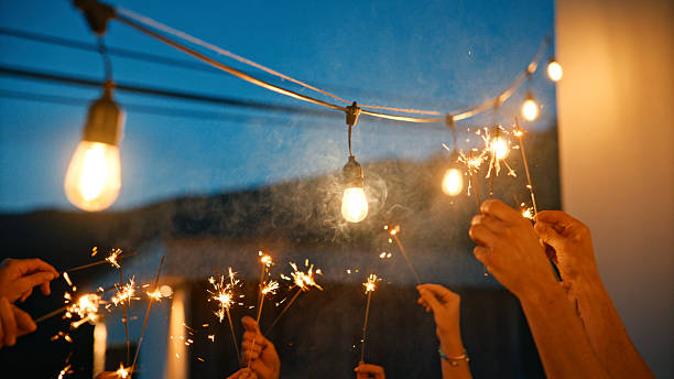 istock Friends Holding Sparklers Celebrating Under String Lights at Dusk 2212535977