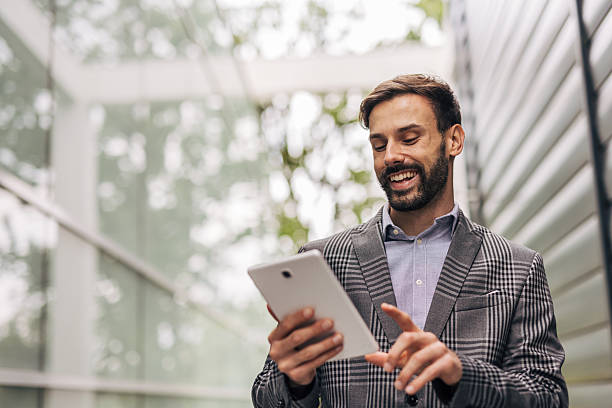 istock Businessman smiling and using digital tablet in urban setting 2212536009