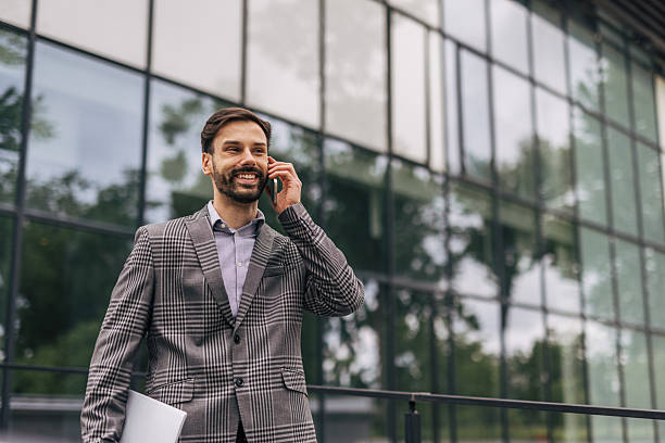 istock Businessman walking and talking on phone outside office building 2212536612