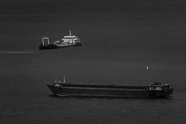 istock black and white, work ship floating in middle of the sea, 2212537519
