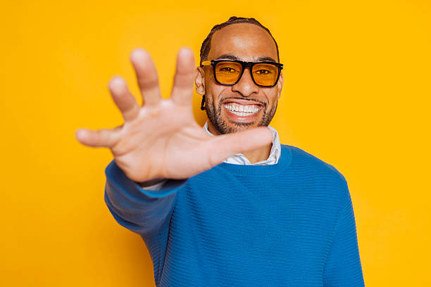 istock Smiling man showing open hand on yellow background 2212541762