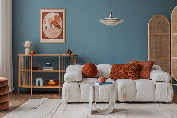 istock A beige textured wall with a simple armchair, a triangular wooden side table with a vase and books, complemented by a minimalist artwork. 2212546984