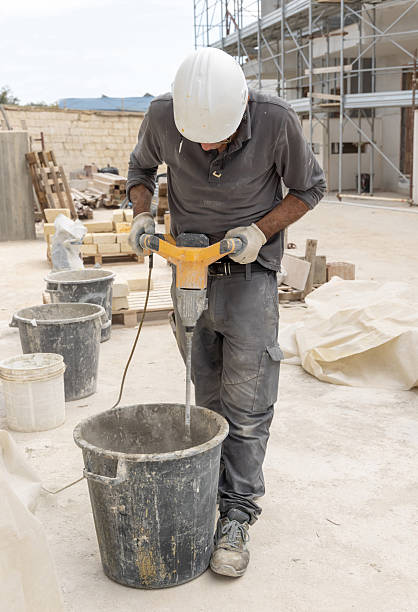 istock Craftsman in grey work clothes mixing cement or plaster with a tool in construction site 2212550221