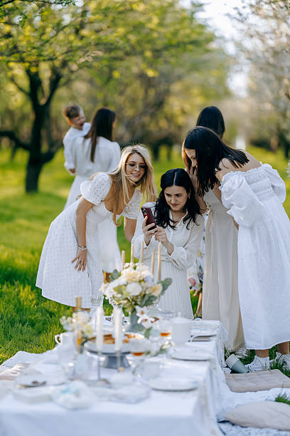 istock Women in elegant white dresses stand around a table in a bright setting 2212552839