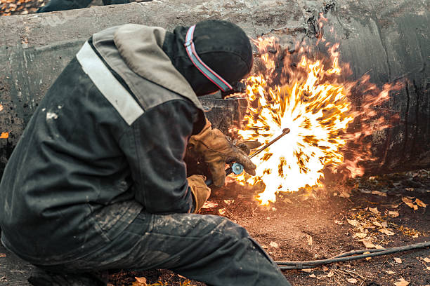istock Male worker cutting metal pipe with torch in outdoor construction site 2212554738