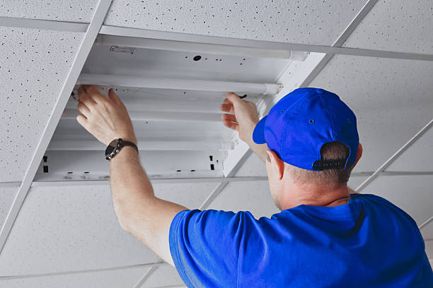 istock Electrician attending to the ceiling light panel installation in office workspace. 2212556441