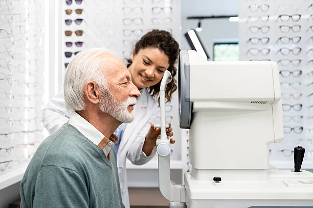 istock Female optometrist positioning senior man to optical instrument and checking eyesight diopter. 2212558043