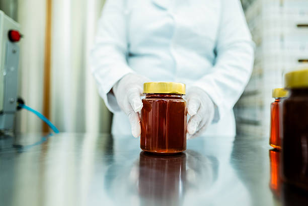 Woman holding a jar on a table in a factory