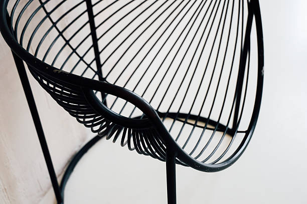 A sleek black wire chair sits prominently in a minimalist space with clean lines and a simple background perfect for modern decor.