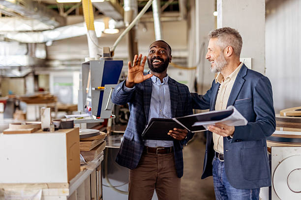 istock Two Business Professionals Discussing Plans in a Manufacturing Facility 2212560386