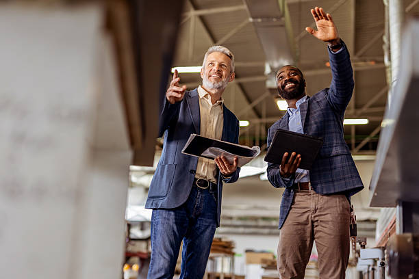 istock Two Business Professionals Discussing Plans Inside a Modern Industrial Workspace 2212560678