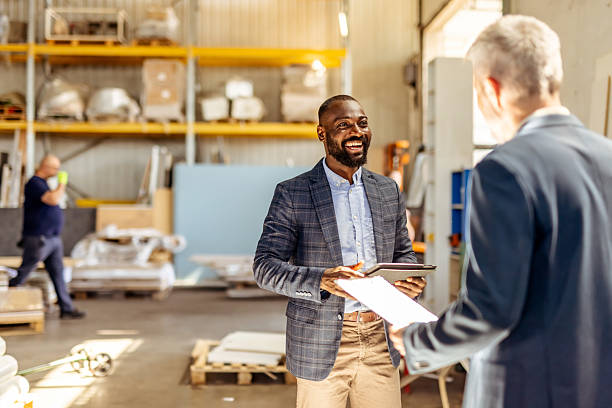 istock Business Professionals Discussing Plans in a Warehouse Environment with Documents and Tablets 2212560934