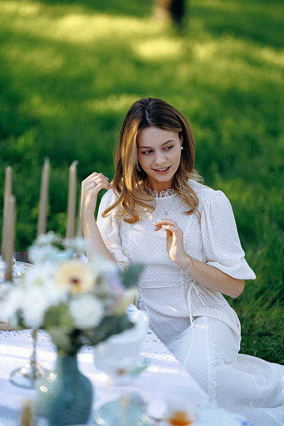 istock A woman in a white dress sits at a table in a serene setting 2212561259