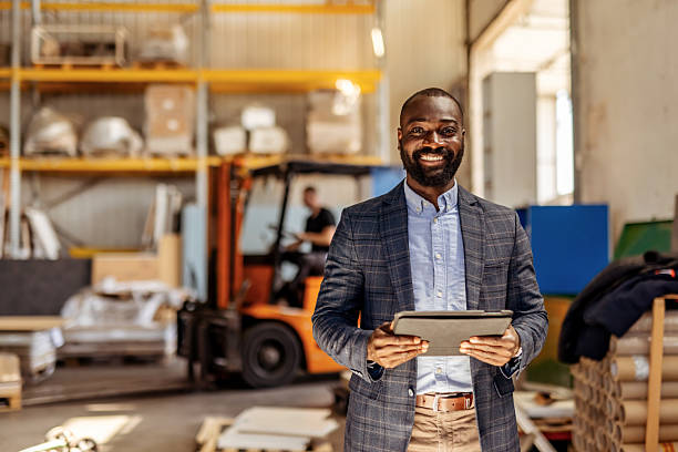 Smiling Businessman Holding a Tablet in a Warehouse Environment