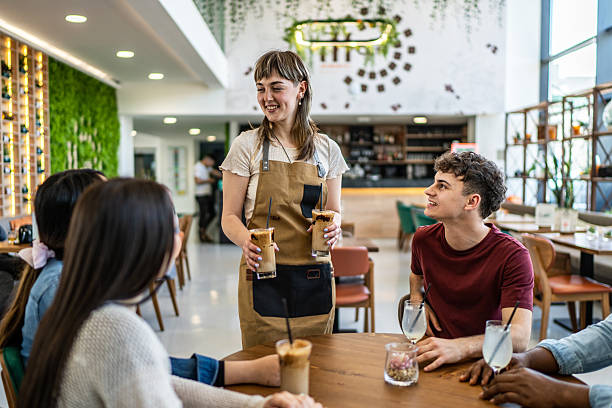 istock Young waitress serving iced coffee to customers at a cafe 2212566681