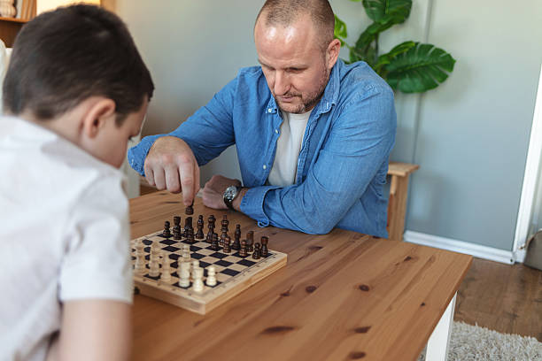 istock Father, son and chess in home with challenge, game or play with strategy for competition. Adorable boy, men and together by board for queen, king and pawn for contest, bonding and retirement. 2212566934