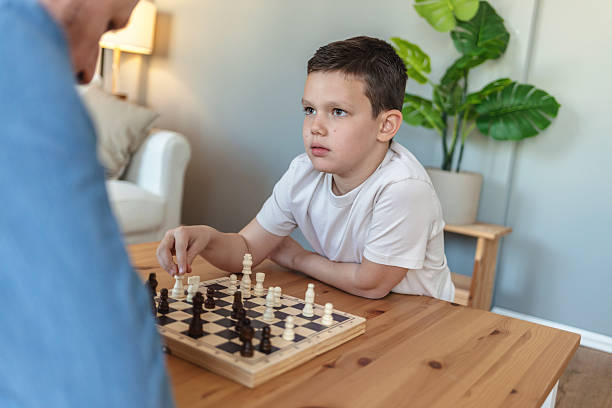 istock Father, son and chess in home with challenge, game or play with strategy for competition. Adorable boy, men and together by board for queen, king and pawn for contest, bonding and retirement. 2212566938
